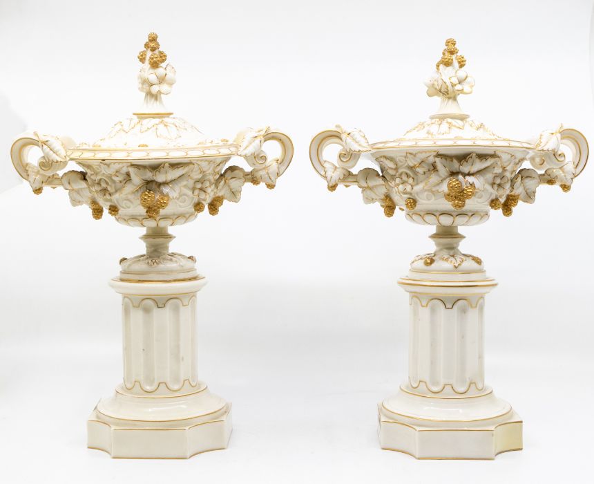 A pair of Royal Worcester lidded urns, on pillars, with fruit and leaf design