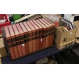 A collection of books including encyclopaedias in a book rack, wooden cane and display sword