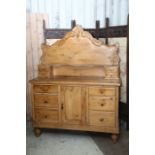 A Victorian pine dressing table, having a tall back with decorative mounts, the base with six