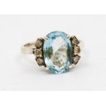 An aquamarine and diamond white metal dress ring, comprising a claw set oval faceted aquamarine