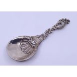 A continental white metal caddy spoon with pierced leafage scroll handle and circular bowl with