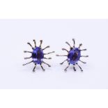 A pair of white metal tanzanite earrings in spiderlike design, each set and faceted tanzanite