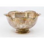 A George V silver bowl, wavy rim punctuated by scroll motifs, on gadroon foot, the body with