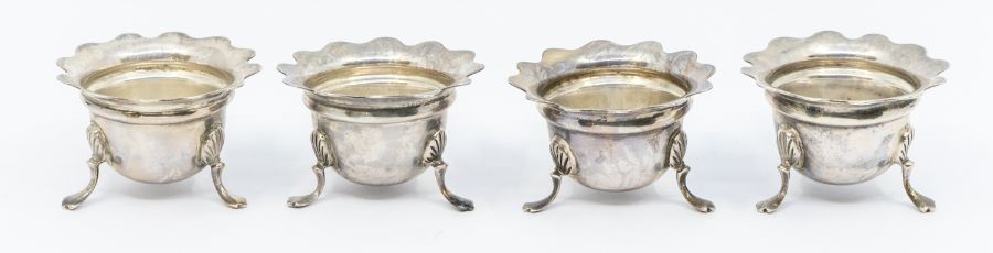 A set of four Edwardian silver salts, flared rims on three shell and trefid feet, hallmarked by