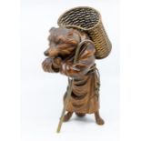 An Asian carved hardwood figure of a fox, wearing robes, carrying a metal basket on his back and
