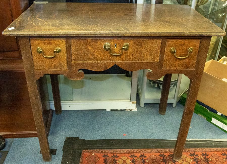 A George III oak lowboy, the moulded top above three drawers, swing handles, square legs, approx