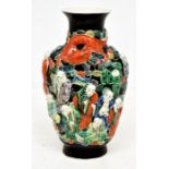 A Chinese vase decorated with raised figures of immortals in red, green, blue and yellow enamels