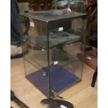 A small glass display case with two glass inside shelves with locking door