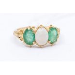 A 9ct gold opal and emerald ring, comprising a central oval opal set either side with oval cut