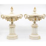 A pair of Royal Worcester lidded urns, on pillars, with fruit and leaf design