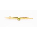 An early 20th Century peridot and 9ct gold bar brooch, round cut peridot set to the centre, matte