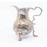 A George II silver baluster cream jug, wavy rim above body later chased with flowers, S scroll