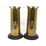 A pair of brass shell case vases on wooden bases, one North Stafford and the other The Lancashire