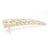 A carved ivory tusk, depicting lions hunting deer and elephant, raised on two carved legs, approx