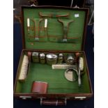 A George V faux crocodile skin vanity case, fitted interior, with glass toilet bottles and plated