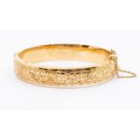 A 9ct gold hinged bangle, hollow form with engraved foliate, width approx 10mm, internal diameter