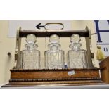 An early 20th Century tantalus, with key and includes three cut glass decanters