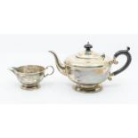 A George VI silver teapot and matching milk jug, plain bodies with beaded rim, the teapot with ebony