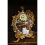 An early 20th Century Rococo style gilt metal mounted combination desk clock and mirror, cartouche