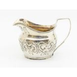 A George III silver cream jug, the body chased with foliage and scrolls, hallmarked by Edward