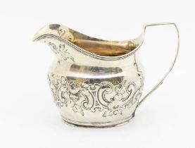A George III silver cream jug, the body chased with foliage and scrolls, hallmarked by Edward