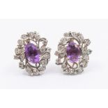 A pair of vintage amethyst and topaz white metal earrings, comprising an oval amethysts claw set