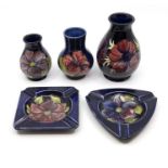 A collection of five pieces of Moorcroft pottery to include three vases and two ashtrays