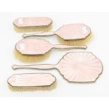 An Art Deco five piece silver mounted and pink enamel dressing table set comprising mirror, two hair