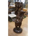 A Black Forest free standing bear holding a branch design basket, and a tray on carved base