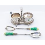 A silver plated sugar bowl and milk jug on stand along with plated salad servers, with green ceramic