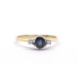 A sapphire and diamond ring, claw set oval cut sapphire and two small diamonds to the shoulders