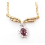 A 9k pendant, claw set oval and ruby surrounded by diamond border with yellow gold bow surmount,