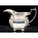 A Georgian style silver cream jug, gadroon border on four ball feet, hallmarked by Adie Brothers,