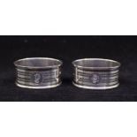 A pair of George V silver engine turned shaped oval napkin rings, each engraved with an initial,