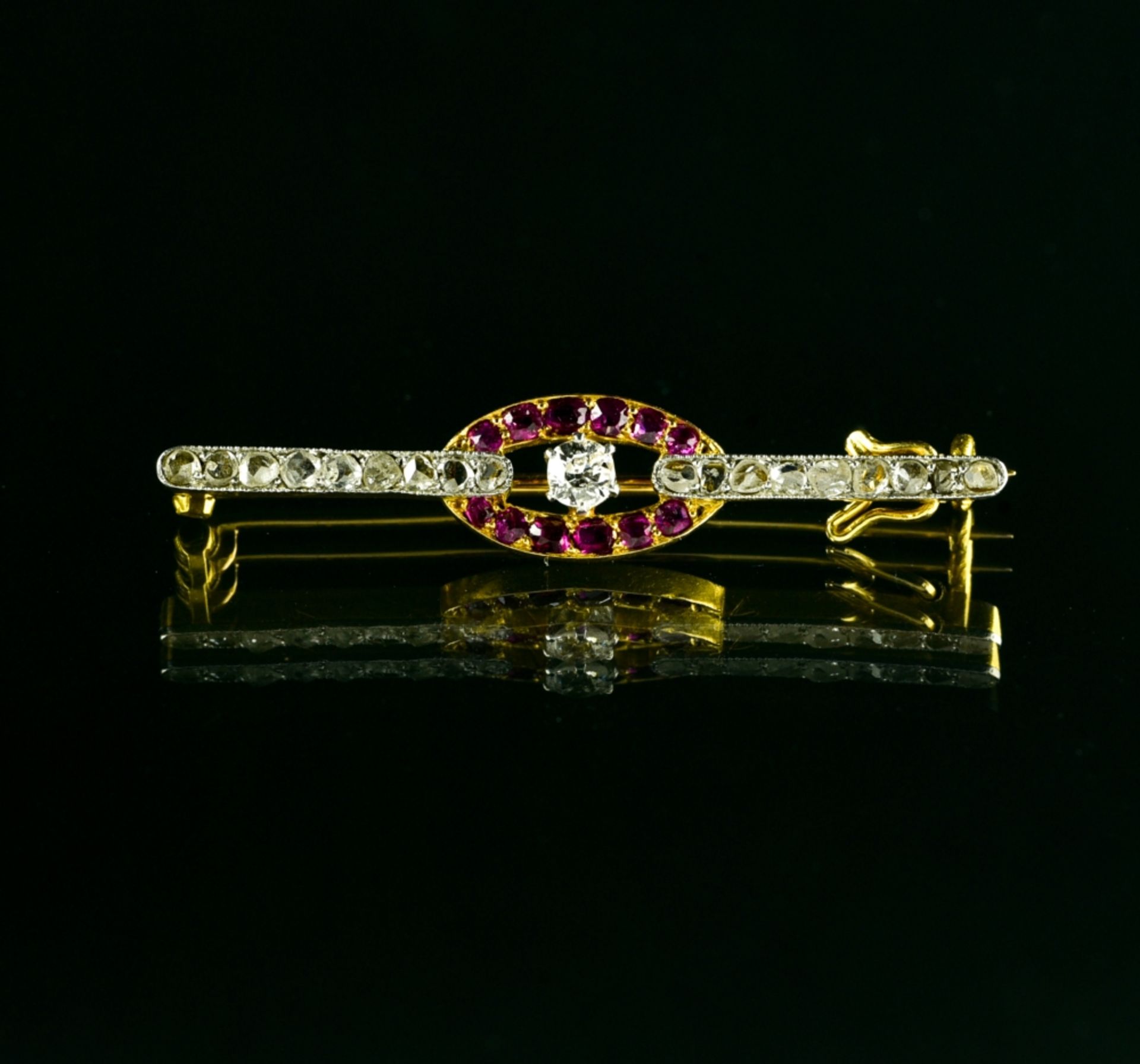 Small brooch 18 kt yellow and white gold, set with small rubies, a diamond, and rose-cut diamonds.