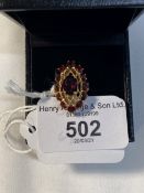 Jewellery: Yellow metal oval garnet cluster ring stamped 750, tests as 18ct gold. Weight 4.9g.
