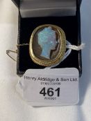 Jewellery: Yellow metal cushion shaped brooch set with tiger's eye and a carved opal cameo of a