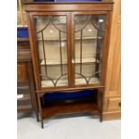 Edwardian mahogany inlaid glazed bookcase on slender supports.