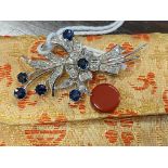 Jewellery: White metal floral spray brooch set with six round cut sapphires, estimated weight of (6)