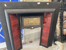 Art Nouveau: Black cast iron fire surround with inset red ceramic tiles to sides, and embossed brass