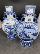 Chinese blue and white decorated moon flask, one with fish motif, the other landscape. Both bear