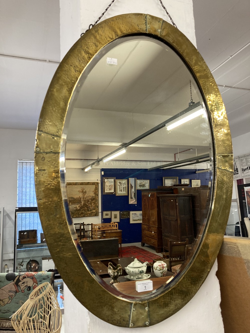 Early 20th cent. Oval beaten brass bevel edged mirror in the Arts and Crafts style. 31ins.