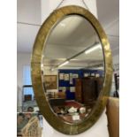 Early 20th cent. Oval beaten brass bevel edged mirror in the Arts and Crafts style. 31ins.