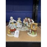 Sitzendorf figures of a couple feeding hens and a rabbit, a small bucolic figure group and two other