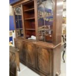 Late George III mahogany library bookcase, the moulded cornice above three glazed doors with