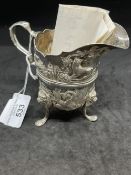 Hallmarked Silver (Irish): Helmet cream jug embossed with country scenes, with a C scroll handle,