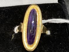 Yellow metal dress ring set with an oblong cabouchon cut amethyst, tests as 18ct gold. Weight 5g.