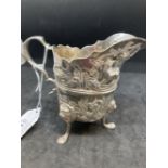 Hallmarked Silver (Irish): Helmet cream jug embossed with country scenes, with a C scroll handle,
