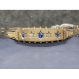 Yellow metal late Victorian bangle set with three sapphires and ten rose cut diamonds, stamped