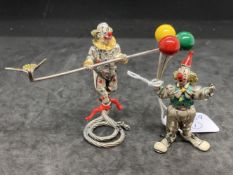 20th cent. White metal and enamel clowns, one with balloons and one walking the tightrope, most